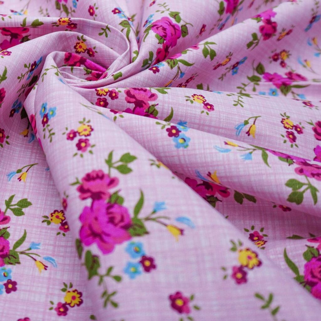 Tricoline rosa-clara com estampa de flores coloridas, disposta em dobras.